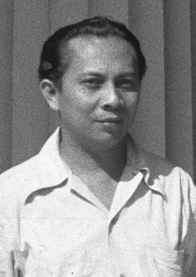 Black-and-white portrait of a man in a light, open-collared shirt.